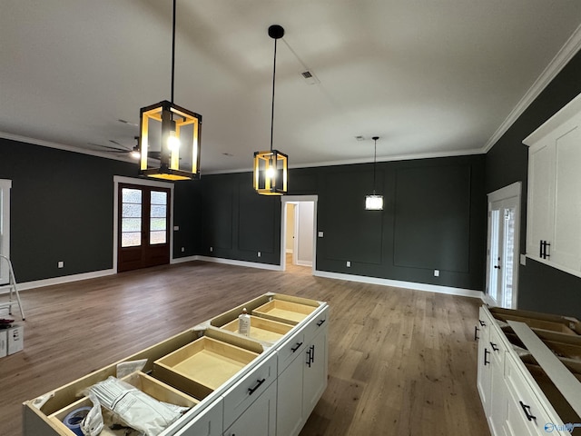 kitchen featuring white cabinetry, pendant lighting, crown molding, and french doors