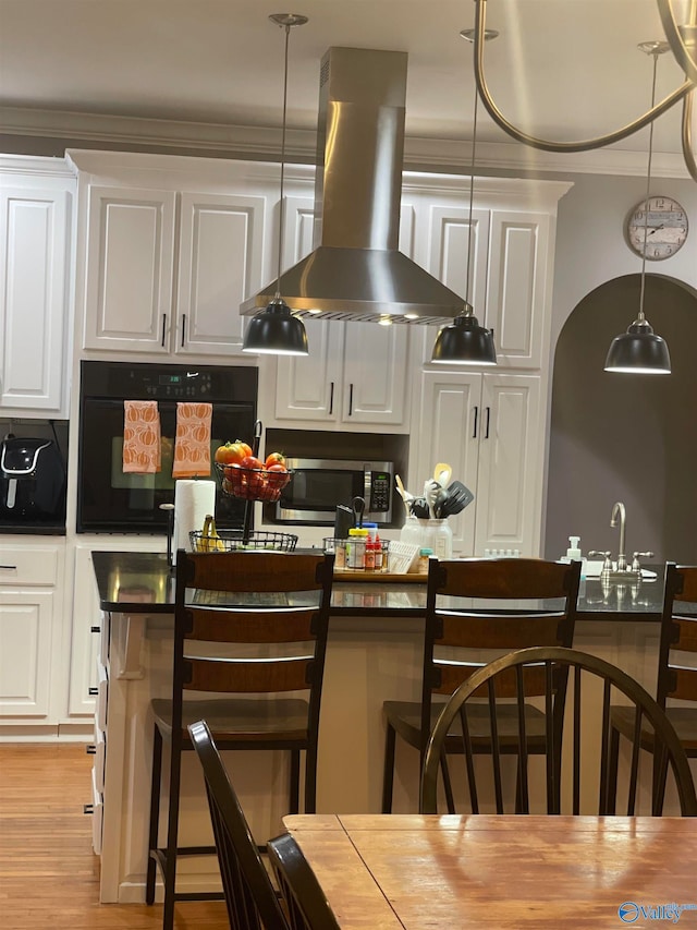 kitchen with extractor fan, light hardwood / wood-style flooring, a kitchen bar, black oven, and white cabinets