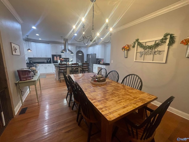 dining room with hardwood / wood-style flooring, an inviting chandelier, and crown molding