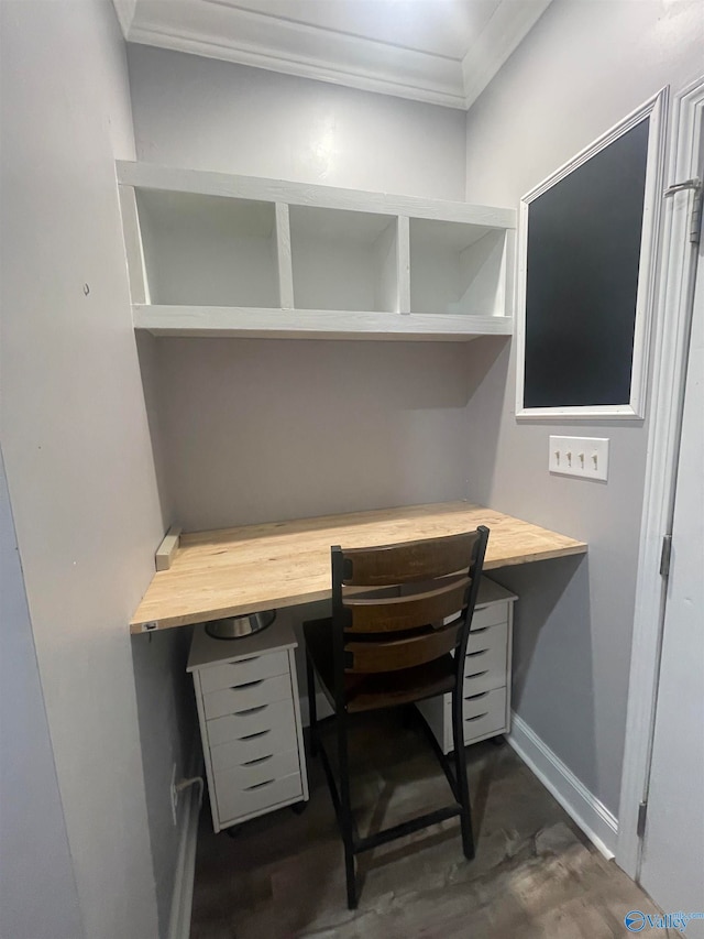 home office featuring built in desk, dark hardwood / wood-style flooring, and crown molding