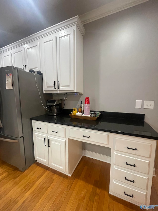 kitchen featuring white cabinets, stainless steel fridge, built in desk, and light hardwood / wood-style floors