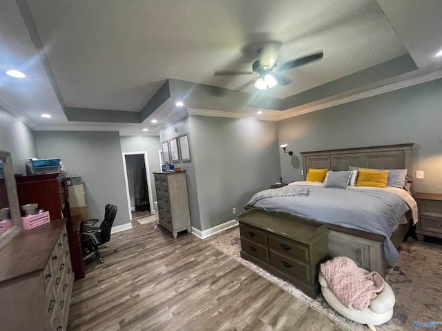 bedroom featuring a raised ceiling, ceiling fan, ornamental molding, and hardwood / wood-style flooring