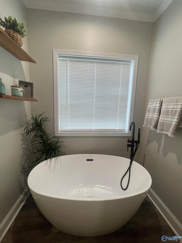 bathroom with crown molding and a tub