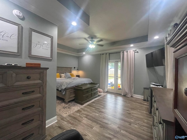 bedroom featuring light hardwood / wood-style flooring, ceiling fan, a tray ceiling, and access to outside