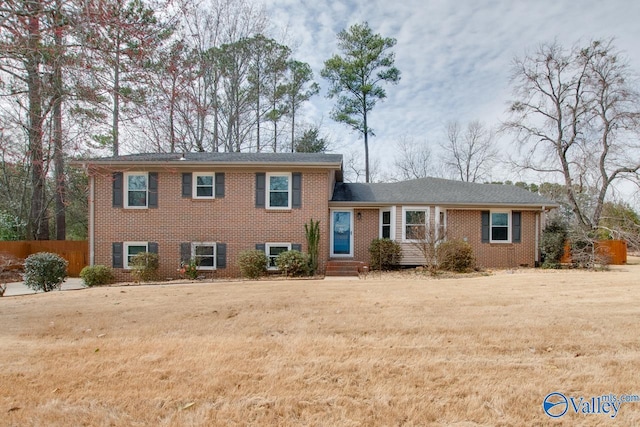 split level home featuring a front yard and brick siding