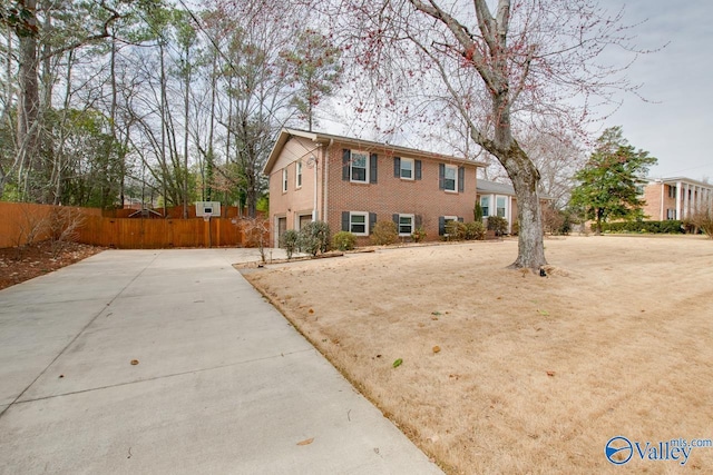 view of front facade featuring an attached garage, driveway, fence, and brick siding