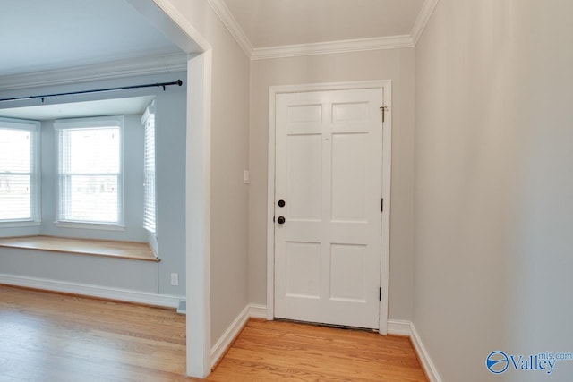 entryway with light wood-style floors, baseboards, and crown molding