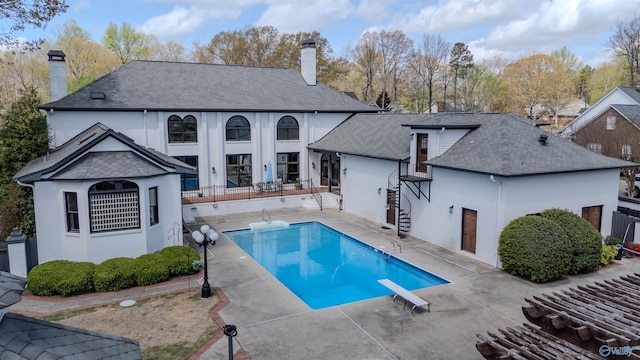 rear view of house with a fenced in pool, a patio area, stucco siding, and a chimney
