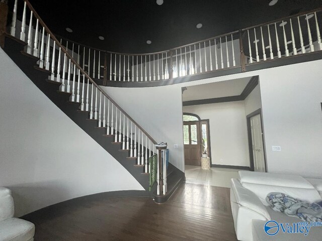 stairs with hardwood / wood-style flooring and a towering ceiling