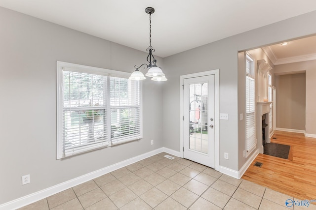 238 Riverwalk Trl, New Market, AL 35716 - unfurnished dining area with crown molding, light tile patterned floors, a fireplace with flush hearth, and a chandelier