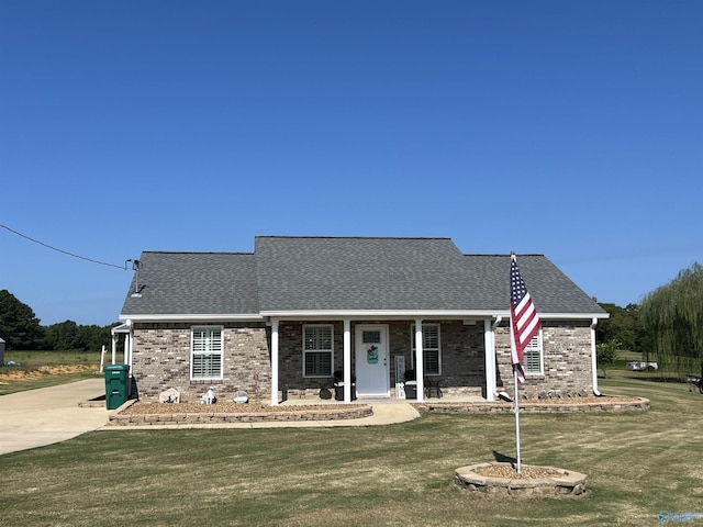 view of front of property with covered porch, brick siding, a front lawn, and roof with shingles