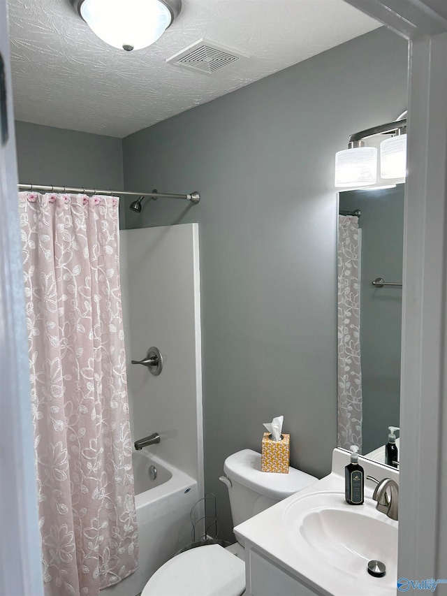 full bathroom featuring toilet, shower / tub combo with curtain, vanity, and a textured ceiling