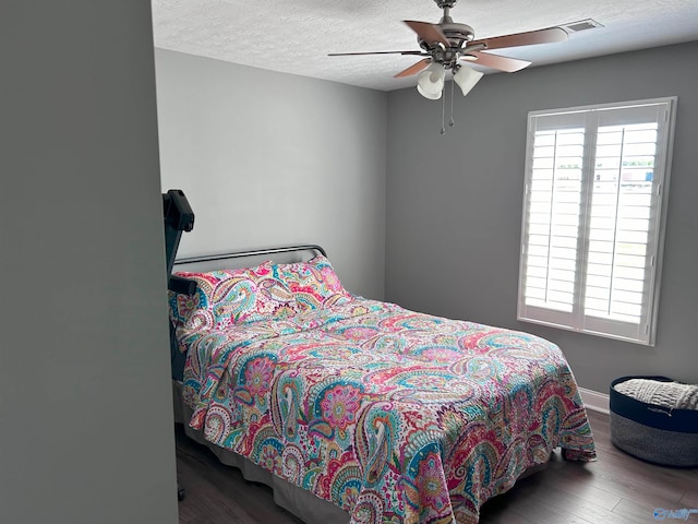 bedroom featuring ceiling fan, hardwood / wood-style floors, and a textured ceiling