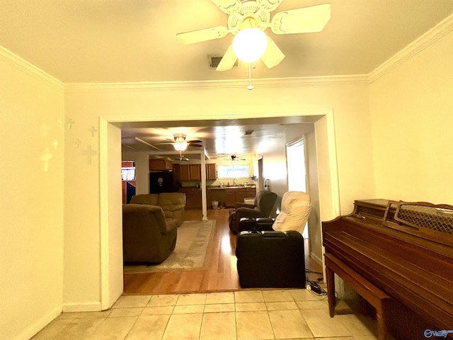 living room with light tile patterned floors, baseboards, ornamental molding, and a ceiling fan