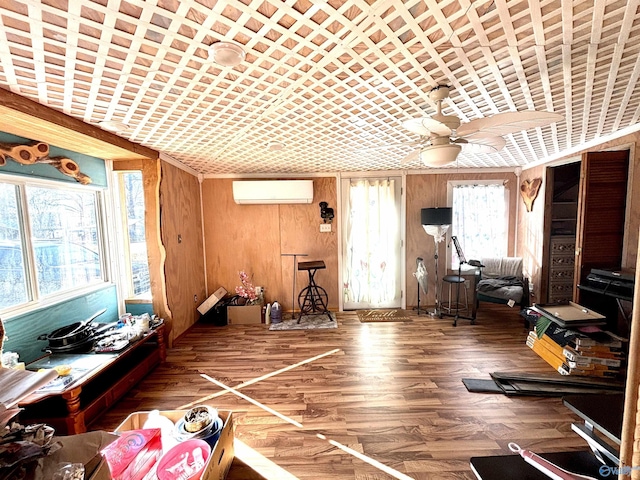 exercise area with a ceiling fan, wood finished floors, wooden walls, and a wall mounted AC