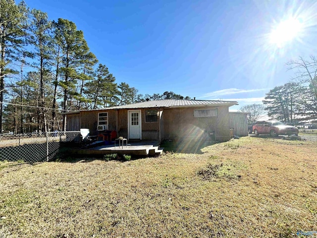 view of front of property with a front yard, metal roof, a wooden deck, and fence