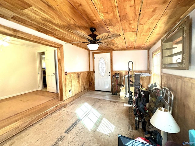 interior space with a wainscoted wall, ceiling fan, wood walls, and wood ceiling