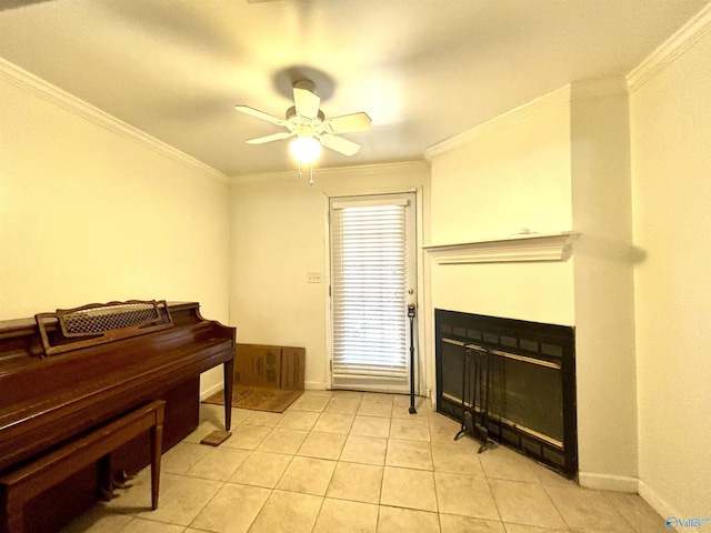 living area featuring light tile patterned floors, ornamental molding, a glass covered fireplace, ceiling fan, and baseboards