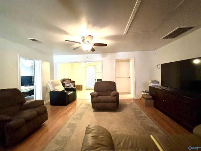 living area featuring attic access, visible vents, ceiling fan, and wood finished floors