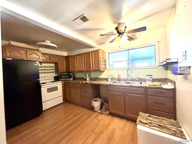 kitchen featuring white range with electric cooktop, visible vents, stainless steel microwave, freestanding refrigerator, and a sink