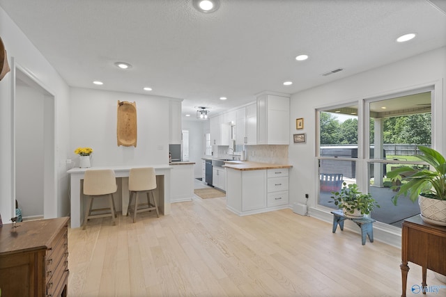 24961 Capshaw Rd, Athens, AL 35613 - kitchen featuring light wood-style flooring, white cabinets, dishwasher, backsplash, and a breakfast bar area