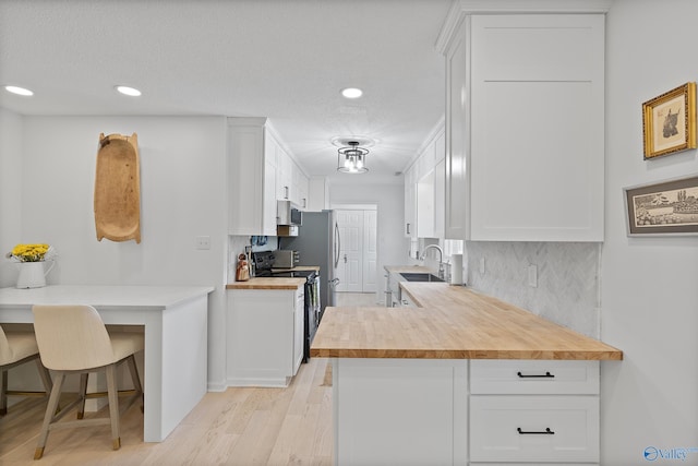 24961 Capshaw Rd, Athens, AL 35613 - kitchen with black electric range oven, stainless steel microwave, white cabinets, backsplash, and recessed lighting