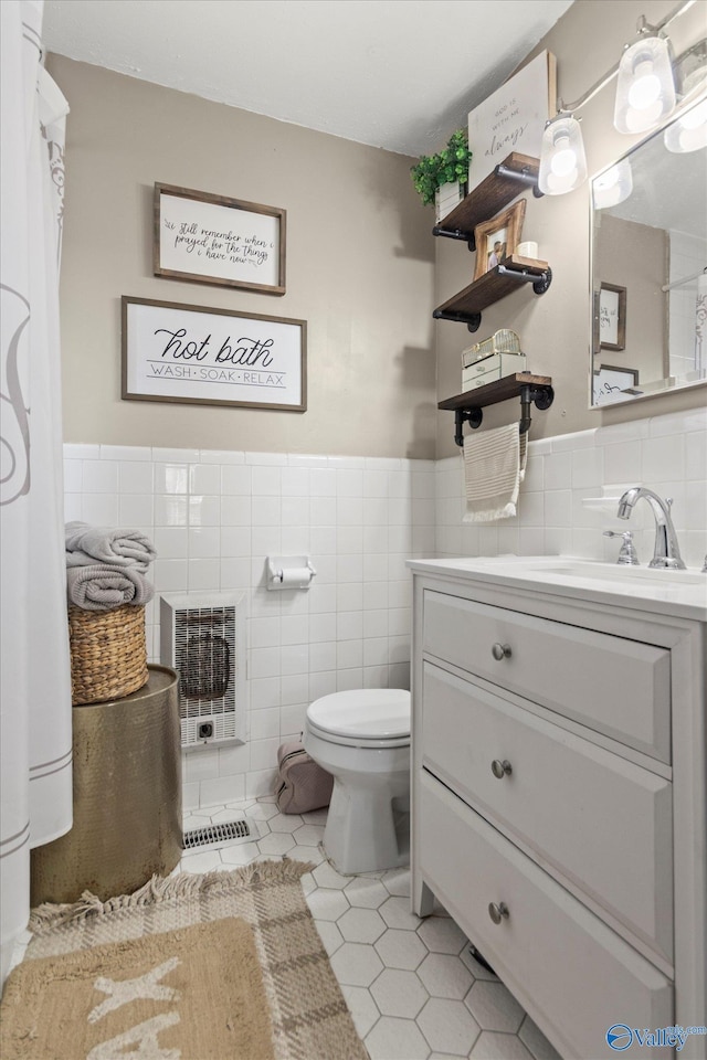 bathroom featuring tile walls, a wainscoted wall, toilet, tile patterned floors, and vanity