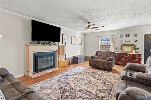 living area featuring a fireplace with flush hearth, ceiling fan, wood finished floors, and ornamental molding