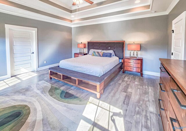 bedroom with a tray ceiling, ornamental molding, and hardwood / wood-style floors