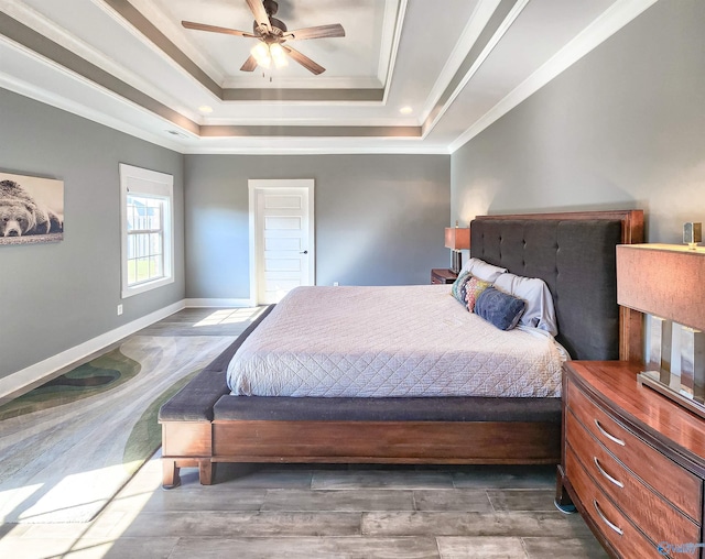 bedroom featuring dark hardwood / wood-style flooring, ornamental molding, a raised ceiling, and ceiling fan