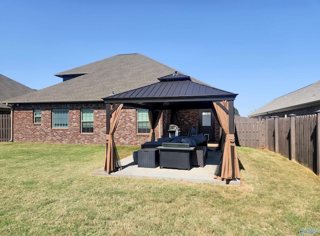 rear view of property featuring a patio area, an outdoor living space, a gazebo, and a lawn