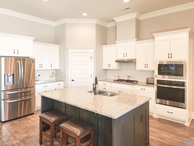 kitchen with sink, stainless steel appliances, white cabinetry, and an island with sink