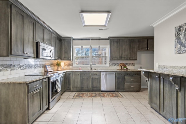 kitchen featuring dark brown cabinetry, stainless steel appliances, light stone countertops, and sink