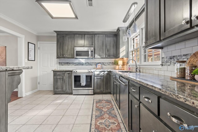 kitchen with sink, light tile patterned floors, dark stone countertops, stainless steel appliances, and decorative light fixtures