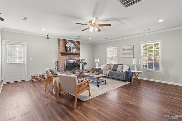 living room featuring a fireplace, crown molding, dark wood-type flooring, and ceiling fan