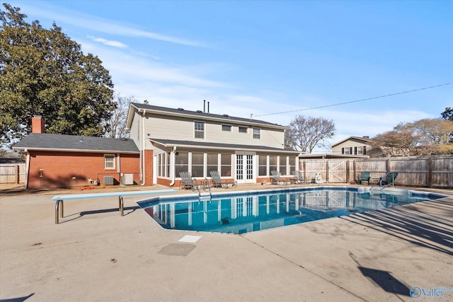 view of swimming pool with french doors, a diving board, a sunroom, cooling unit, and a patio