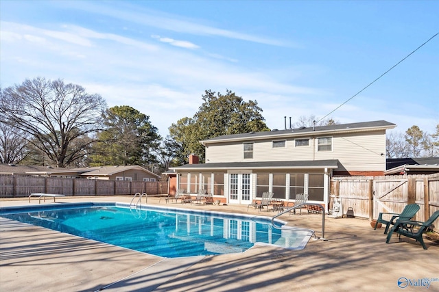 view of swimming pool featuring a sunroom, a diving board, and a patio