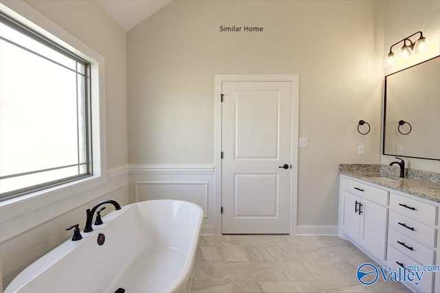 bathroom featuring vanity, lofted ceiling, and a bath