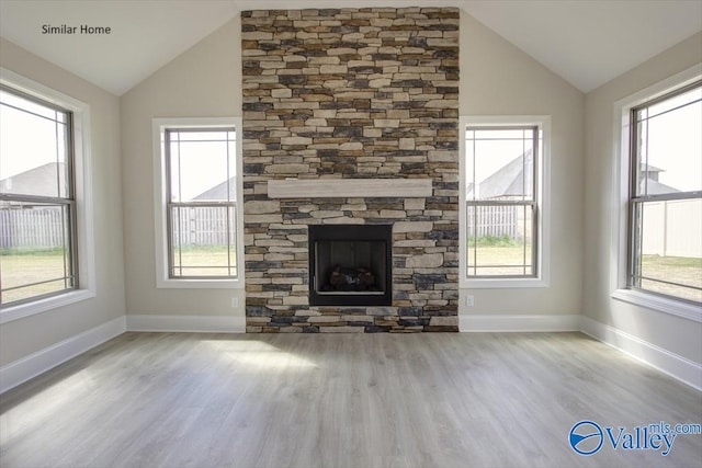 unfurnished living room with a fireplace, vaulted ceiling, light hardwood / wood-style flooring, and a wealth of natural light