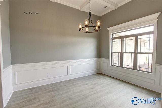 unfurnished room featuring beam ceiling, ornamental molding, light wood-type flooring, and a chandelier