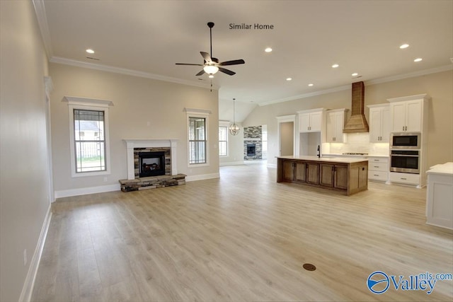 unfurnished living room with light hardwood / wood-style flooring, ceiling fan, a fireplace, ornamental molding, and vaulted ceiling