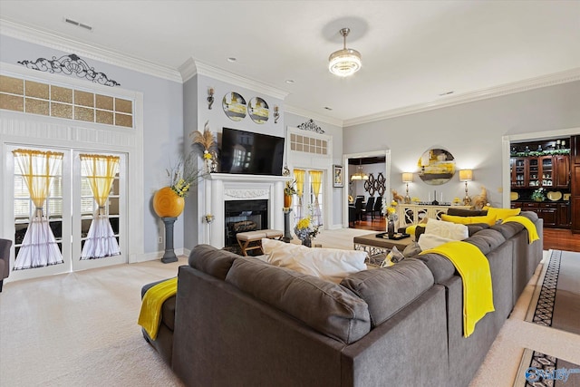 living room featuring carpet floors, visible vents, ornamental molding, a glass covered fireplace, and baseboards