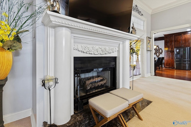 interior details with a fireplace, ornamental molding, carpet flooring, refrigerator with ice dispenser, and baseboards