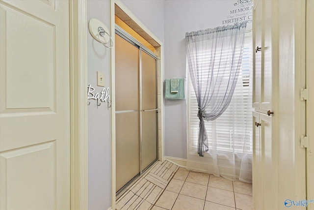 bathroom with a shower with door and tile patterned floors