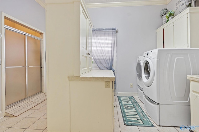 clothes washing area with cabinet space, baseboards, ornamental molding, washing machine and clothes dryer, and light tile patterned flooring