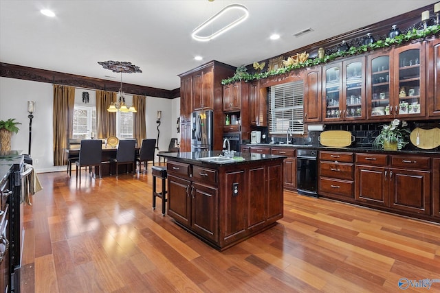 kitchen featuring a breakfast bar area, light wood finished floors, tasteful backsplash, visible vents, and stainless steel fridge with ice dispenser