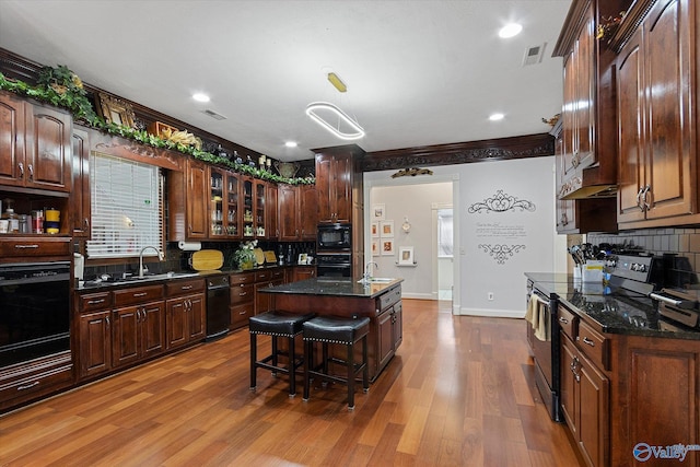 kitchen with tasteful backsplash, visible vents, a sink, wood finished floors, and black appliances
