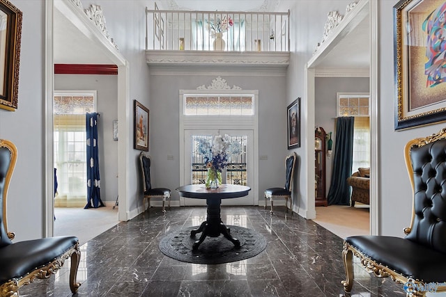 entryway with marble finish floor, crown molding, a towering ceiling, and baseboards