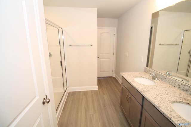 bathroom featuring hardwood / wood-style floors, vanity, and a shower with door