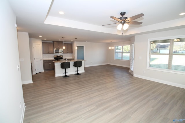 unfurnished living room with ceiling fan with notable chandelier, hardwood / wood-style flooring, a raised ceiling, and sink